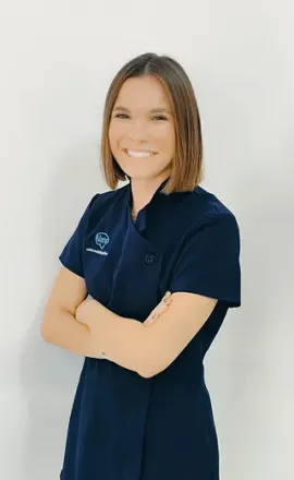 Una mujer con un vestido azul está de pie con los brazos cruzados y sonriendo.