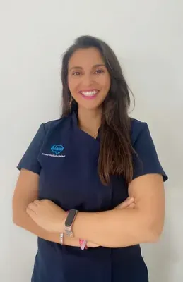 Una mujer con una blusa azul posa para una fotografía con los brazos cruzados.