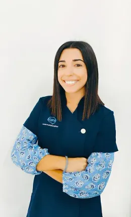 Una mujer con un uniforme azul posa para una fotografía con los brazos cruzados.